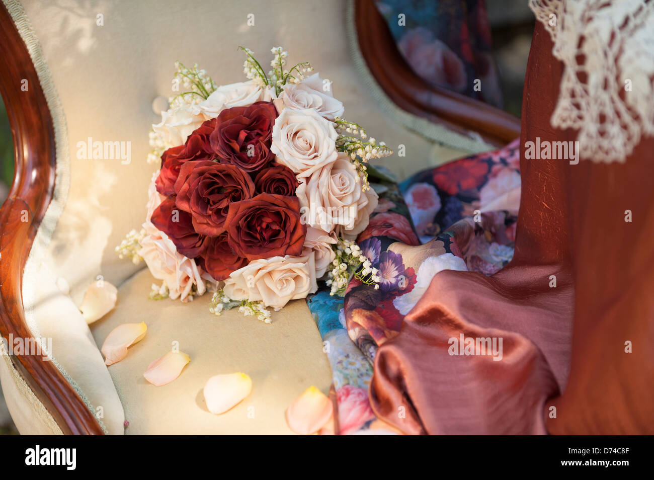 Bouquet of red and pink roses on an old fashioned high back chair Stock Photo