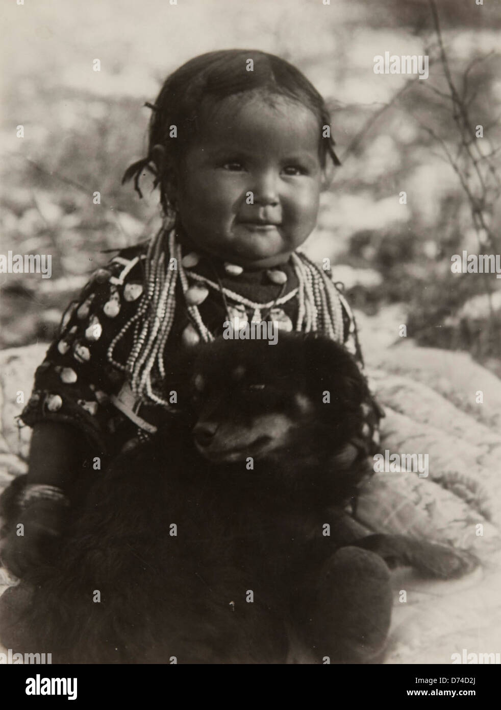 This portrait features a Native American child with a dog, captured in a historical photograph by the Museum of Photographic Arts. The child is adorned with beads, representing Native American culture and heritage. Stock Photo