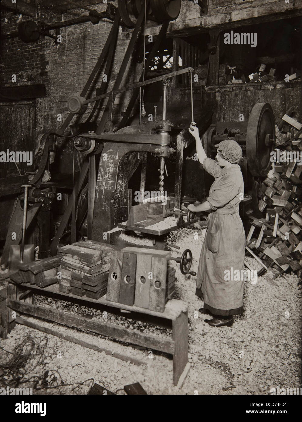 A photograph from the 1910s shows a woman operating a boring machine to ...