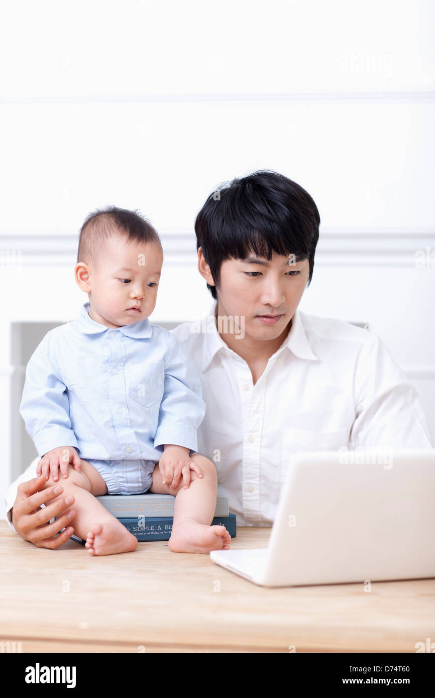 father using laptop with a baby on table Stock Photo - Alamy