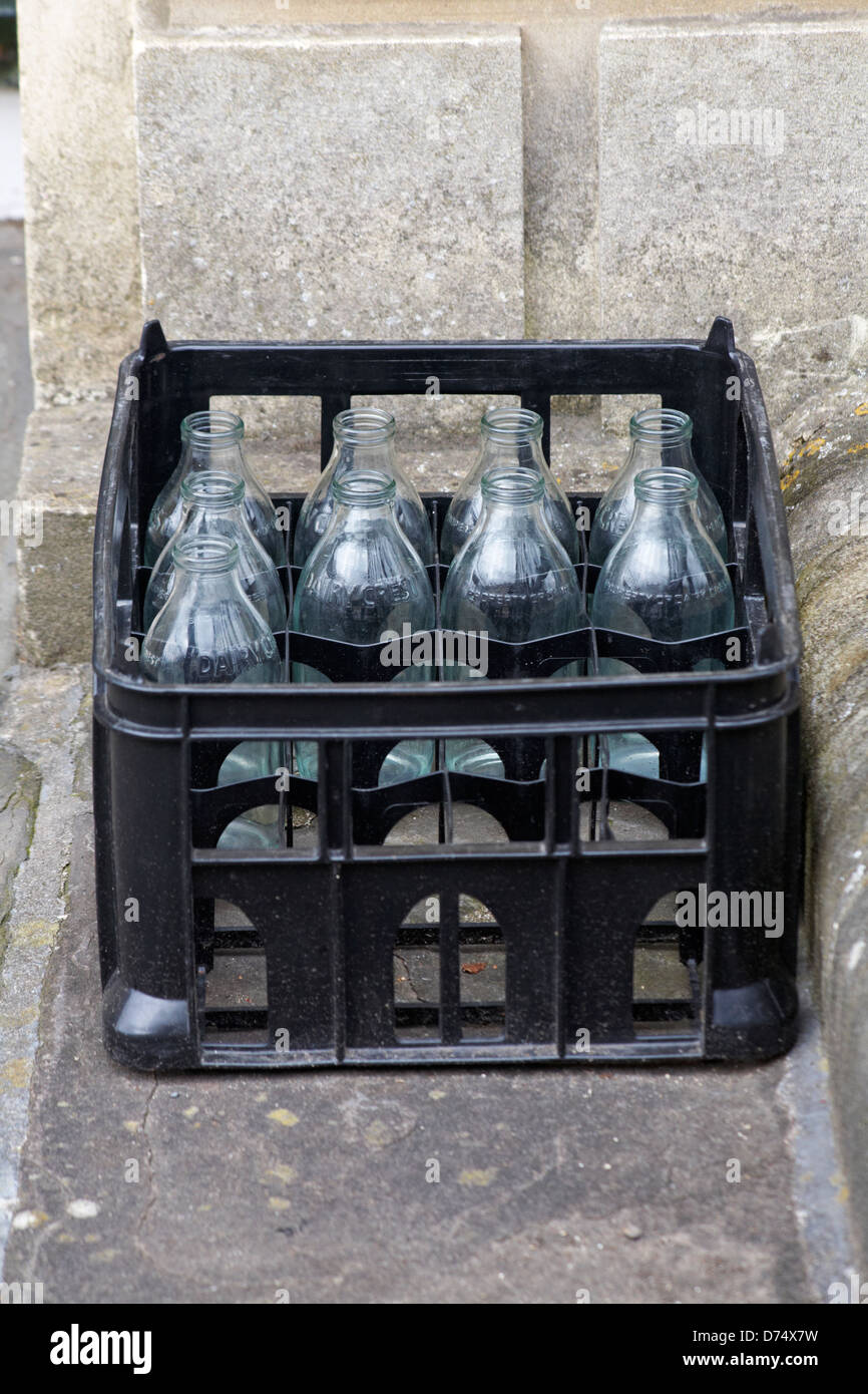 crate of Dairy Crest nine empty glass milk bottles on doorstep in UK Stock Photo