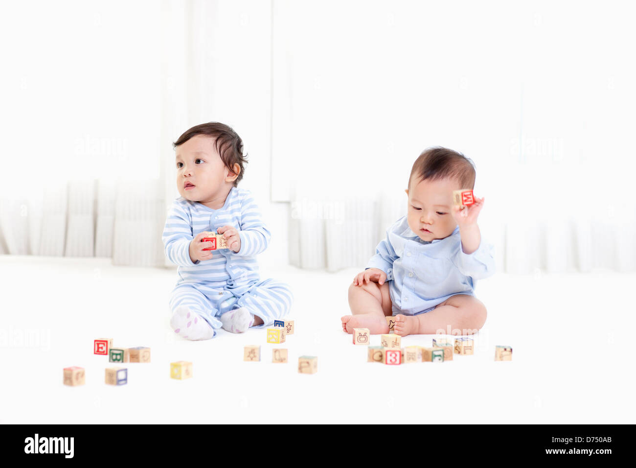 two babies playing with blocks on the floor Stock Photo Alamy