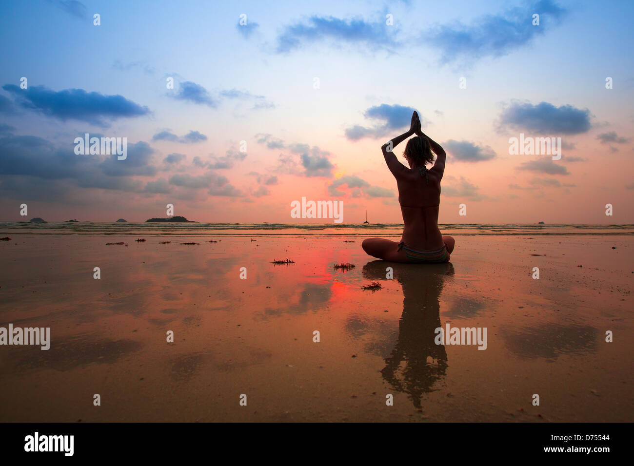 Silhouette young woman practicing yoga on the beach at sunset Stock Photo