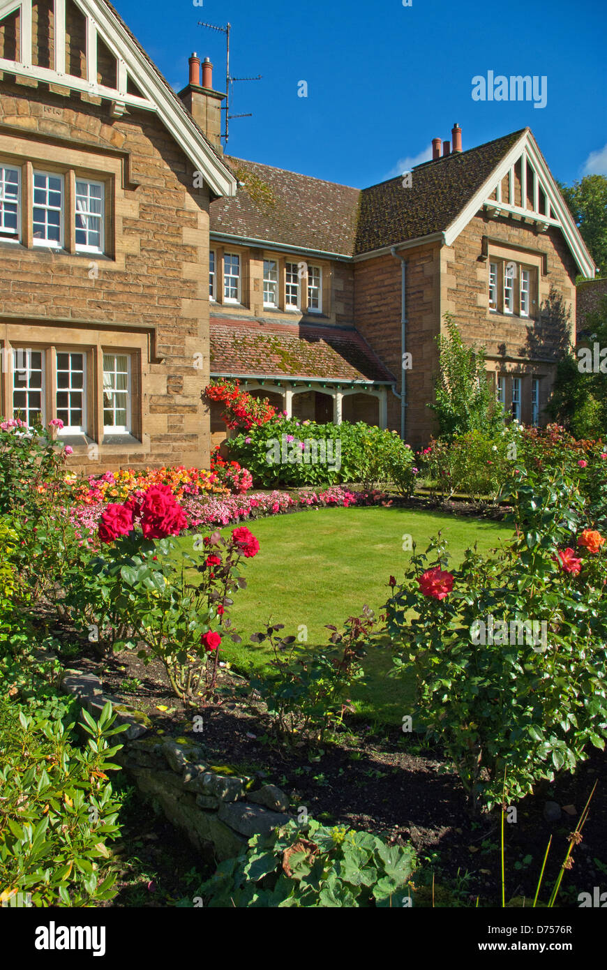 Mellow stone house in the village of Ford, with a front lawn surrounded by flowers and shrubs Stock Photo
