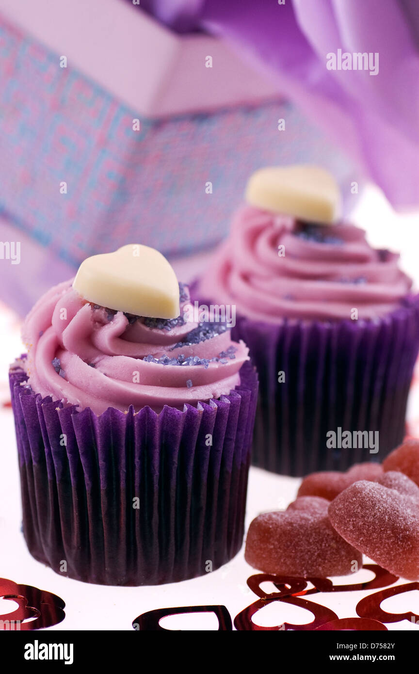 Sainsbury in store baked lilac coloured cupcakes topped with love heart chocolates and butter cream served with love heart jelly Stock Photo