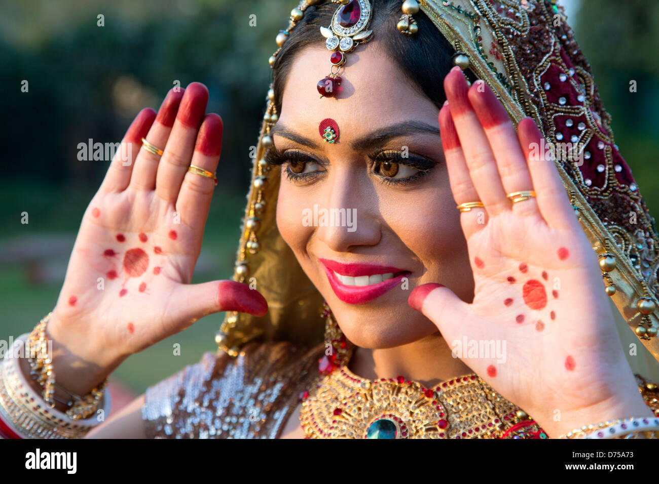 Beautiful Indian Bride in traditional Hindu wedding attire with lehnga,  bridal bangles and shy pose, adjusting her netted veil with her hands.  Stock Photo | Adobe Stock