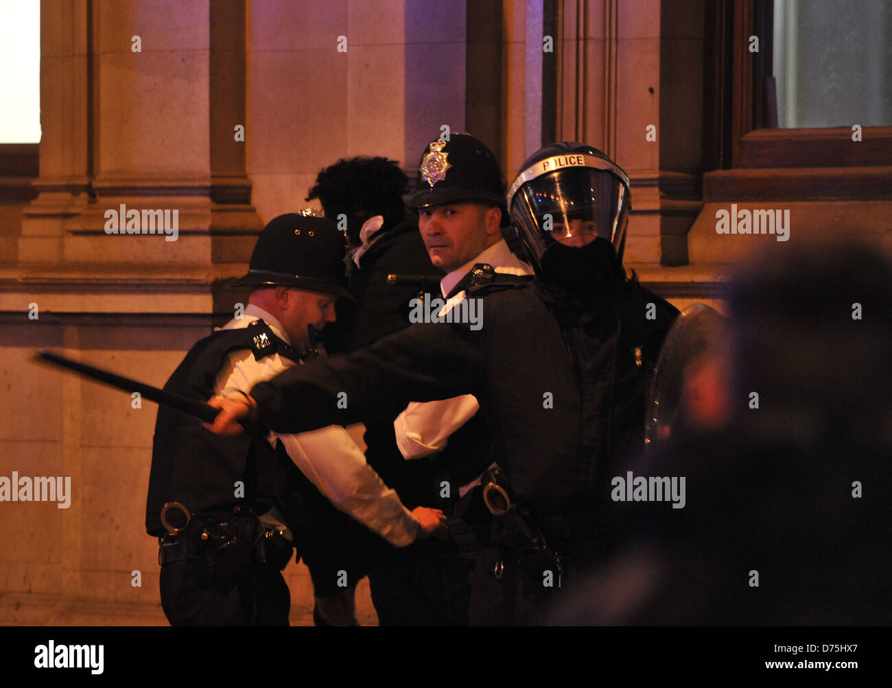 Police officers detain a man as rioters attack shops and property during an unrest in North London's Camden Town on August 9, Stock Photo