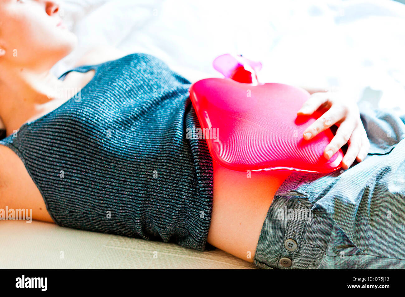 woman using a hotwater bottle on her belly to releive abdominal pain