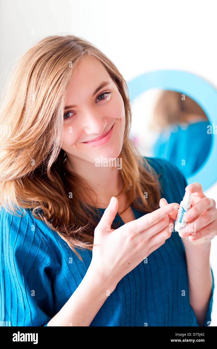 woman applying cream on her lips as a treatment for a cold sore. Stock Photo