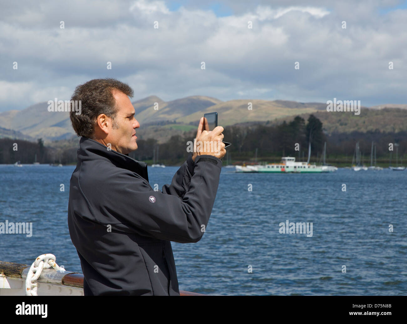 Man taking pictures on his iPad tablet computer, Lake Windermere, Lake District National Park, Cumbria, England UK Stock Photo
