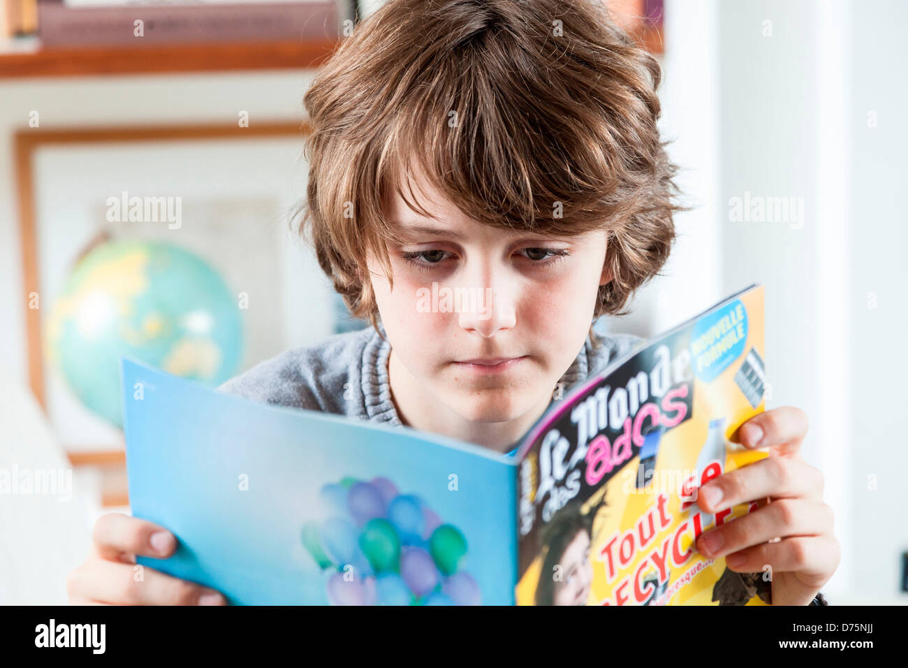 12 year old boy reading a news magazine Stock Photo Alamy