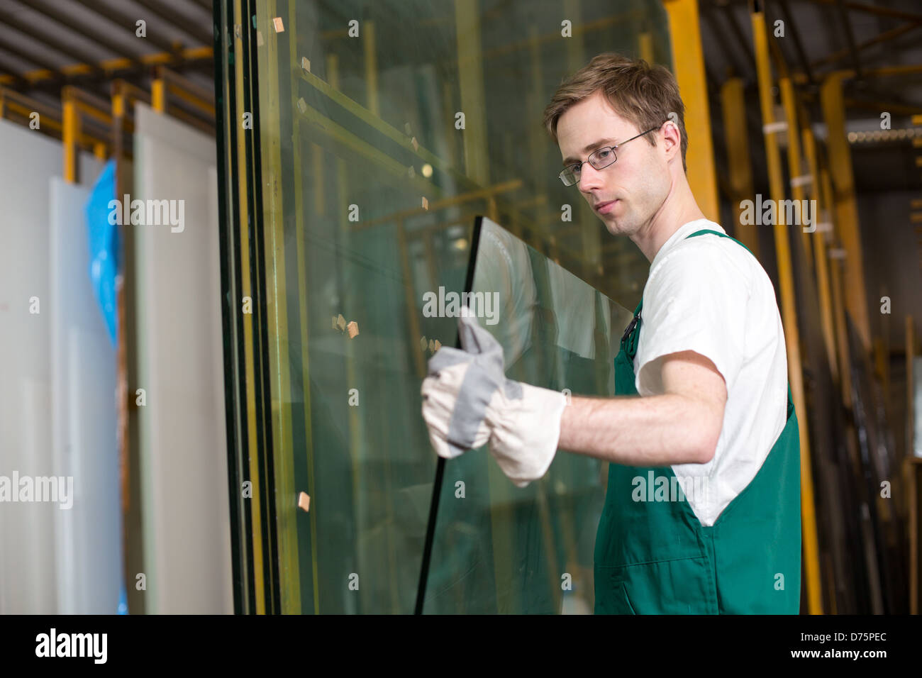 Worker in glazier's workshop, warehouse or storage handling glass Stock Photo