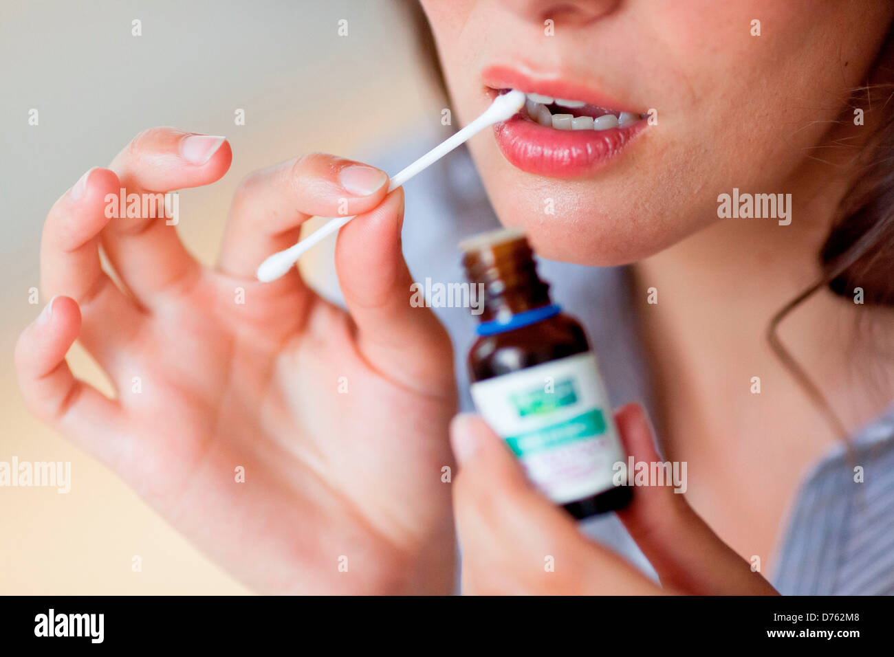 Woman using essential oil of cloves to relieve a toothache Stock Photo