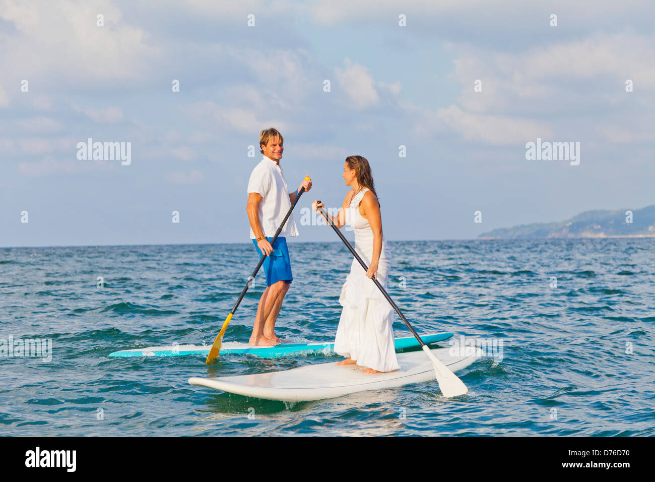 Dressed up man and woman riding paddle boards Stock Photo