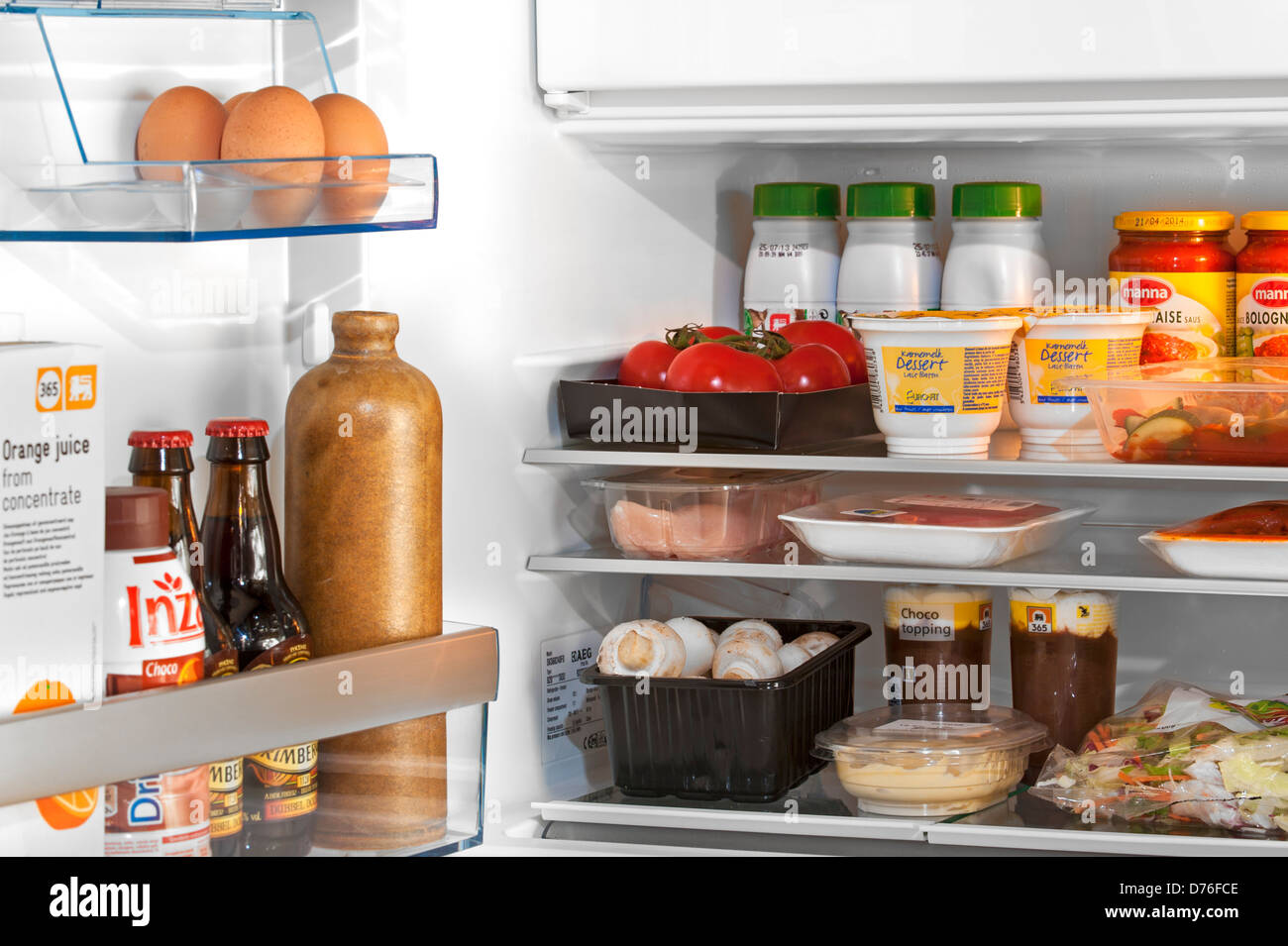 Cooled food and beverages in open fridge / refrigerator in kitchen Stock Photo