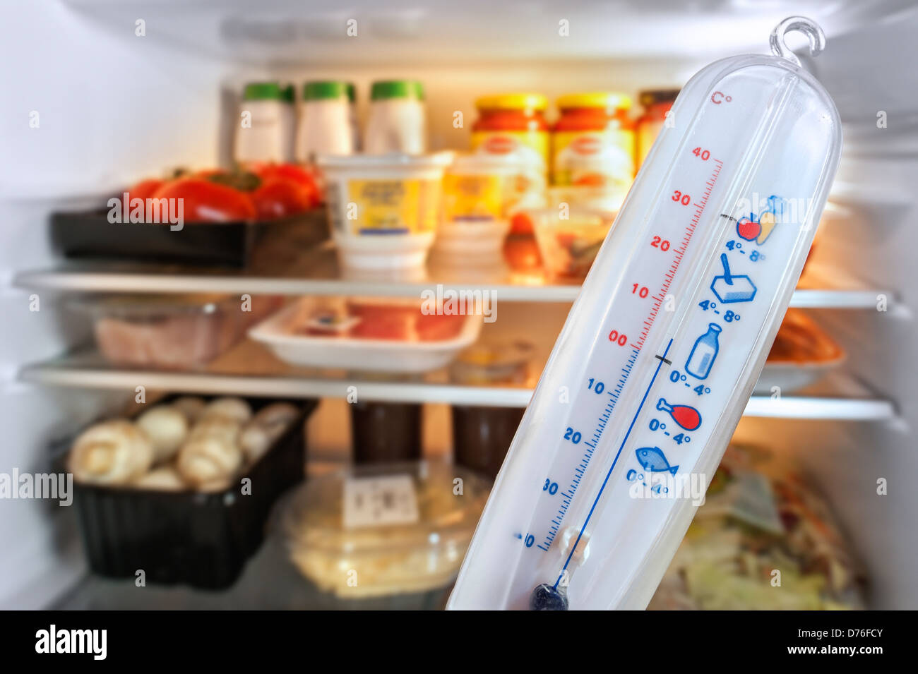 Thermometer in front of open fridge / refrigerator in kitchen Stock Photo