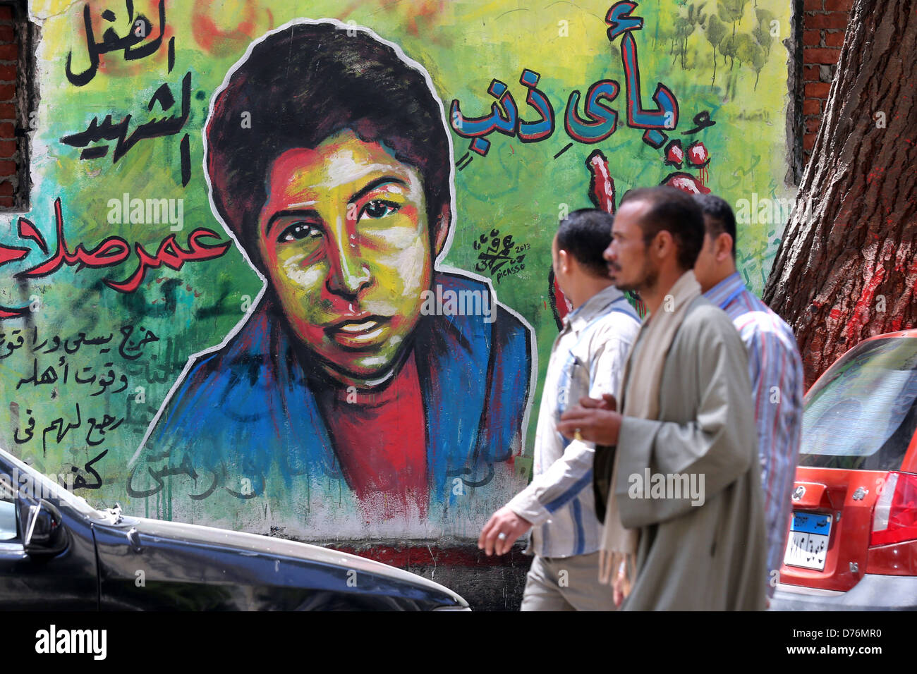 Men walking in front of a revolutionary mural on a wall of martyrs near Tahrir Square in Cairo. Stock Photo