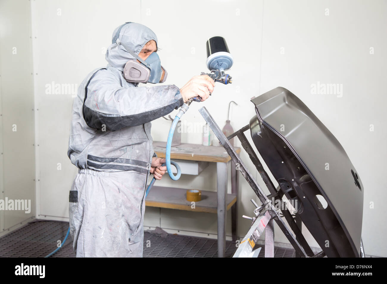 Car body painter spraying paint or color on bodywork in a garage or