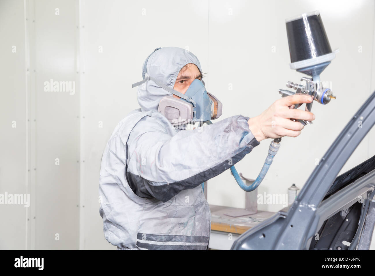 Car body painter spraying paint or color on bodywork in a garage or