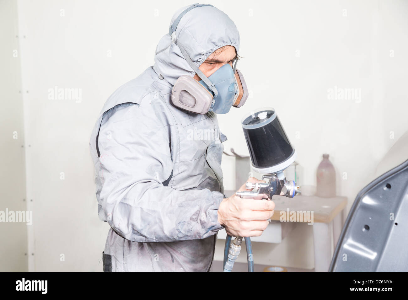 Car body painter spraying paint or color on bodywork in a garage or