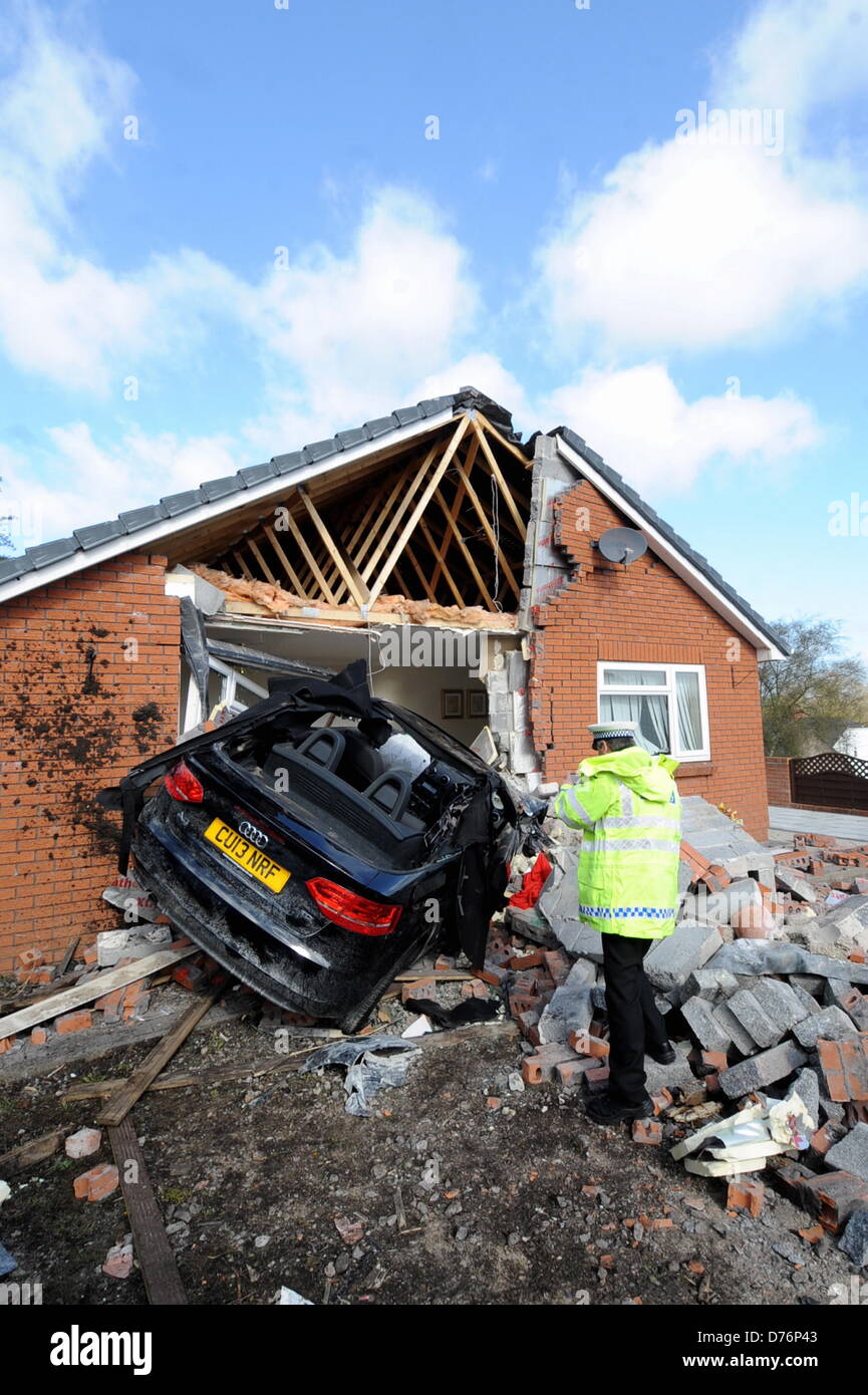 Gowerton, UK. 29th April 2013  A police officer is examining the scene of an accident in which a bungalow belonging to Marianne Heath in Gowerton, near Swansea, UK, was partially destroyed when a brand new Audi convertible car plunged into the lounge whilst she was having breakfast in the kitchen. Credit:  D Legakis / Alamy Live News Stock Photo