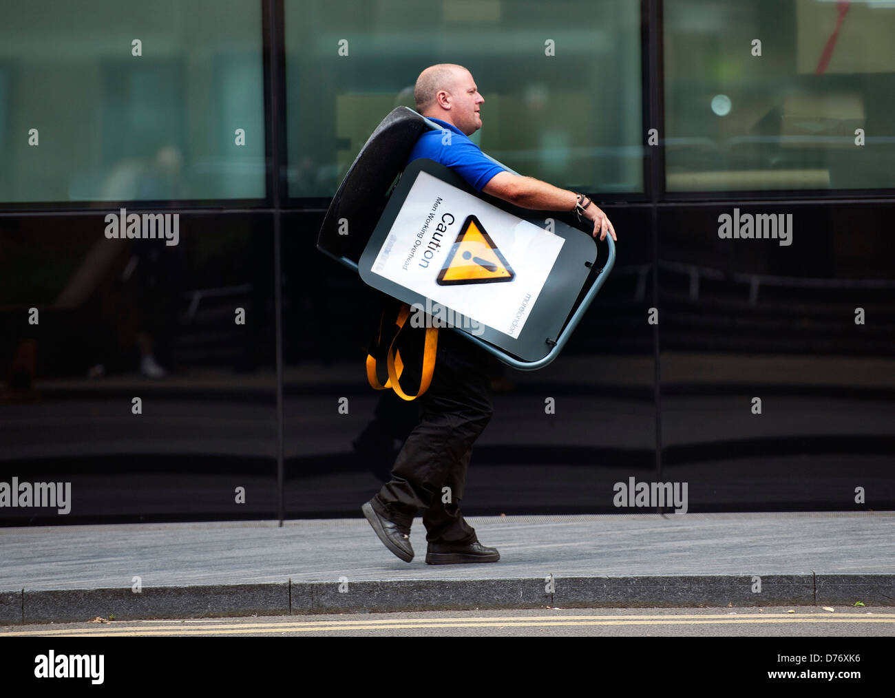 Man carrying Caution sign over his shoulder Stock Photo