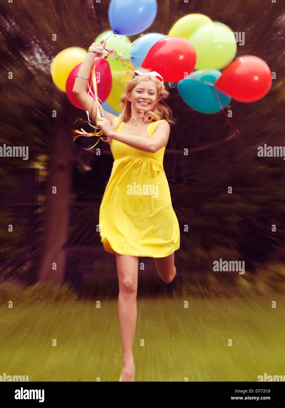 Happy young woman in summer dress running with colorful balloons Stock Photo