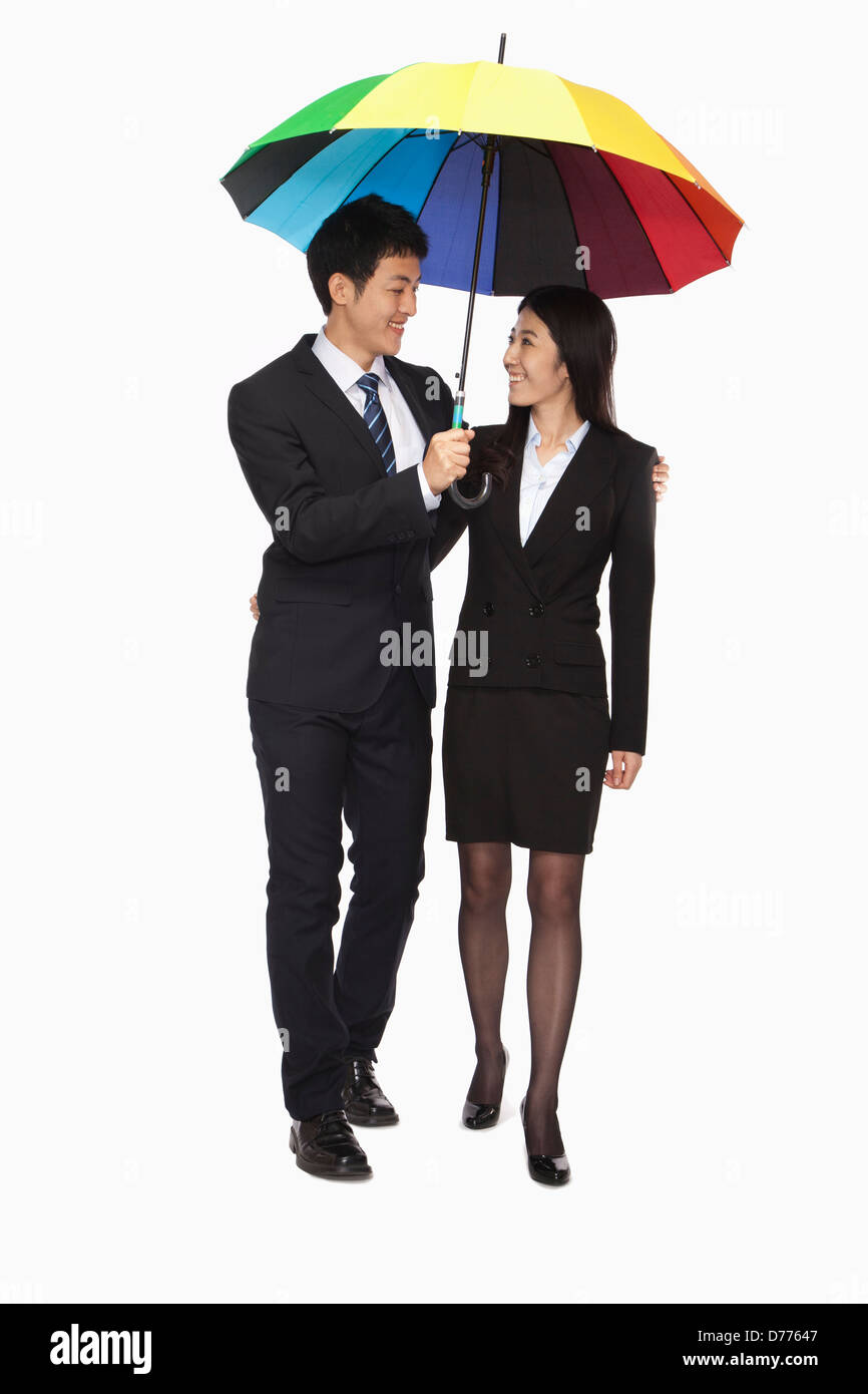 Businessman and businesswomen walking under colorful umbrella Stock Photo