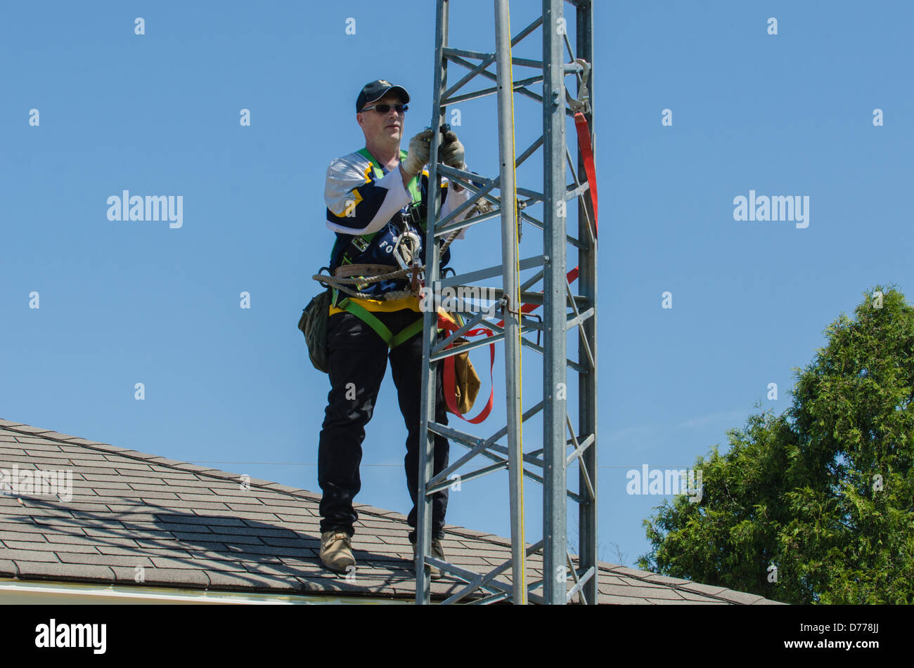 Man climbing antenna tower during amateur radio tower installation. Stock Photo