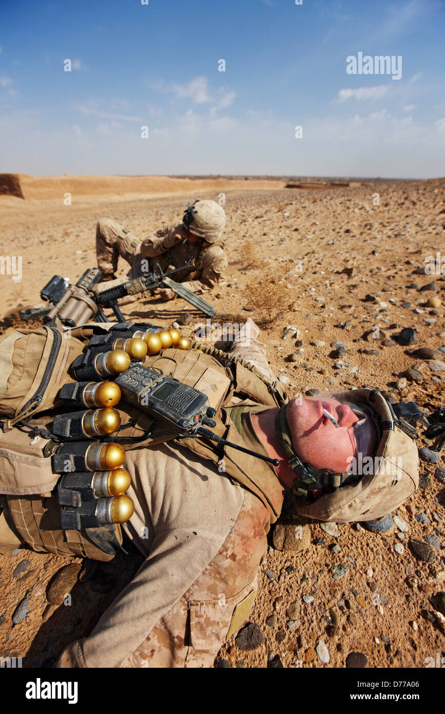 A U.S Marine Wearing Belt 40mm High Explosive Grenades Rests Smokes Cigarette During Combat Operation in Afghanistan's Helmand Stock Photo
