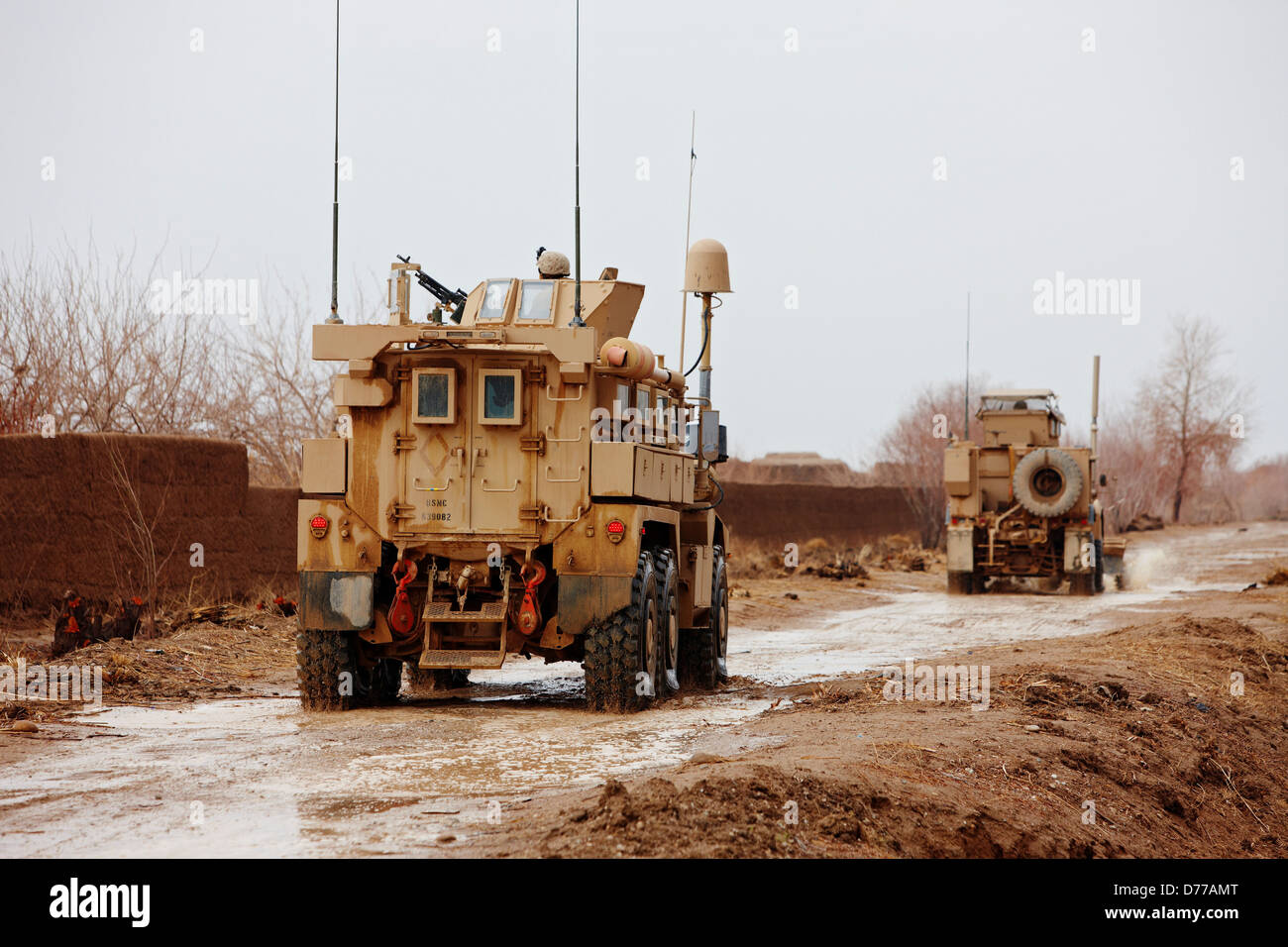 Convoy U.S. Marine Corps MRAPs or Mine Resistant Ambush Protected Vehicles Drive Through Muddy Road Helmand Province Afghanistan Stock Photo