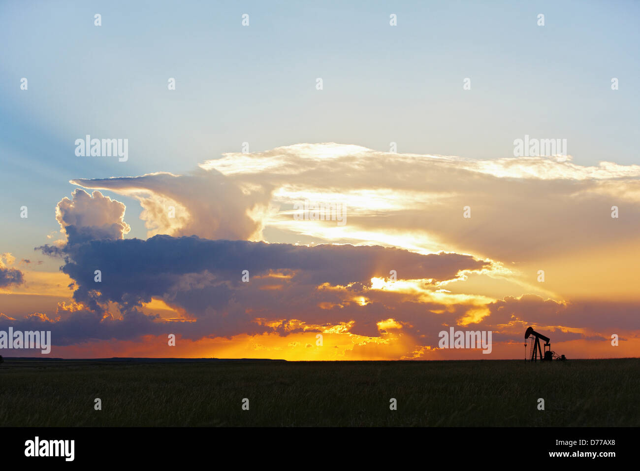 Oil Well Pump Jack at Sunset Distant Thunderstorm Stock Photo