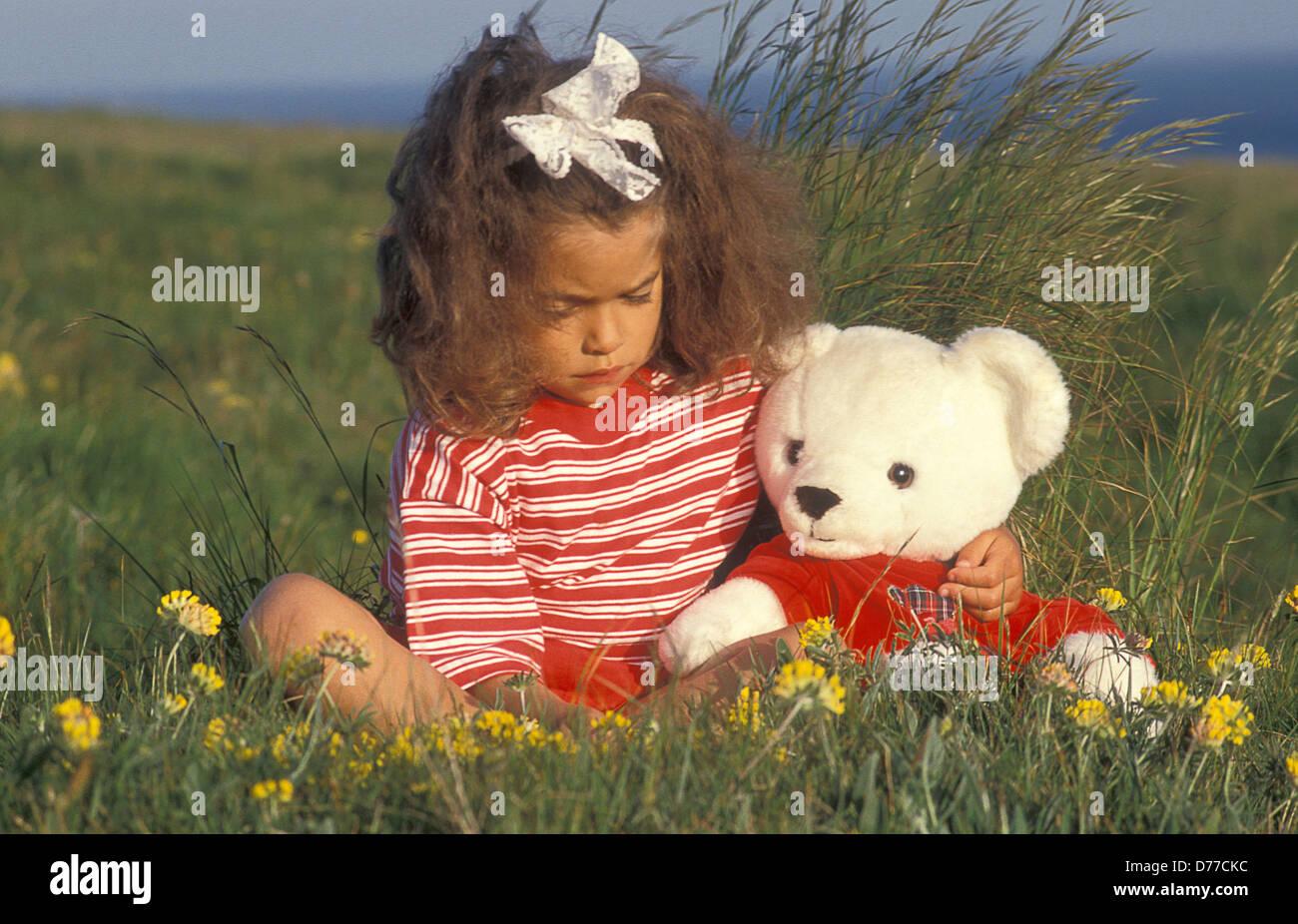 little girl sitting in field with teddy bear Stock Photo - Alamy
