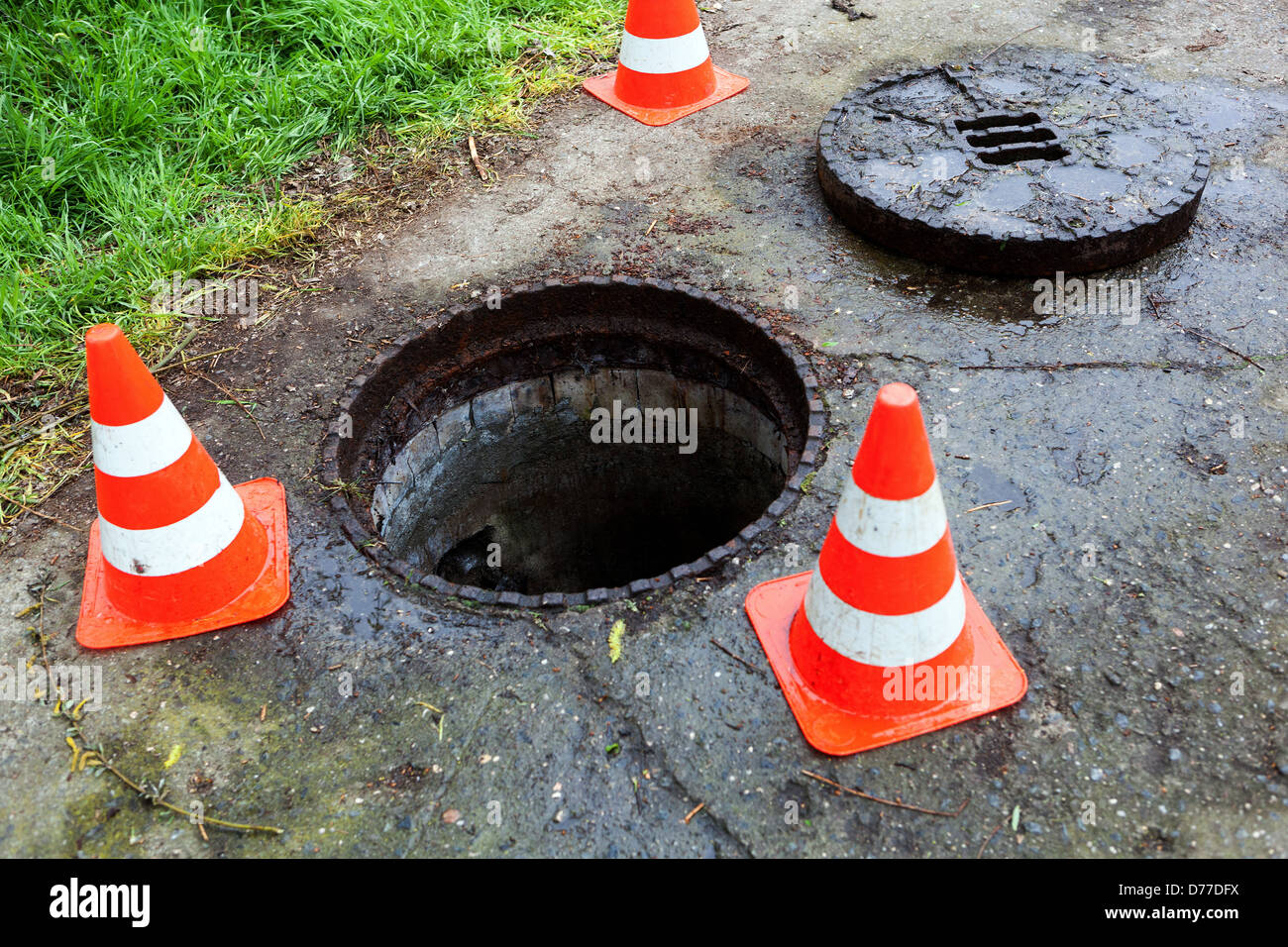 Open manhole cover, uncovered hole marked with cones, hatch Stock Photo
