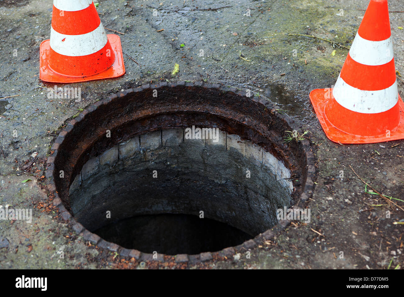 Open manhole cover with traffic cones Stock Photo
