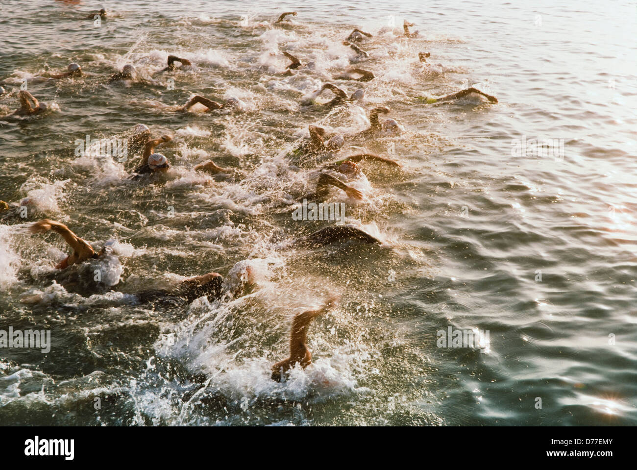 Start of Ironman Triatalon, competitors swimming in ocean, motion effects and splash. Stock Photo