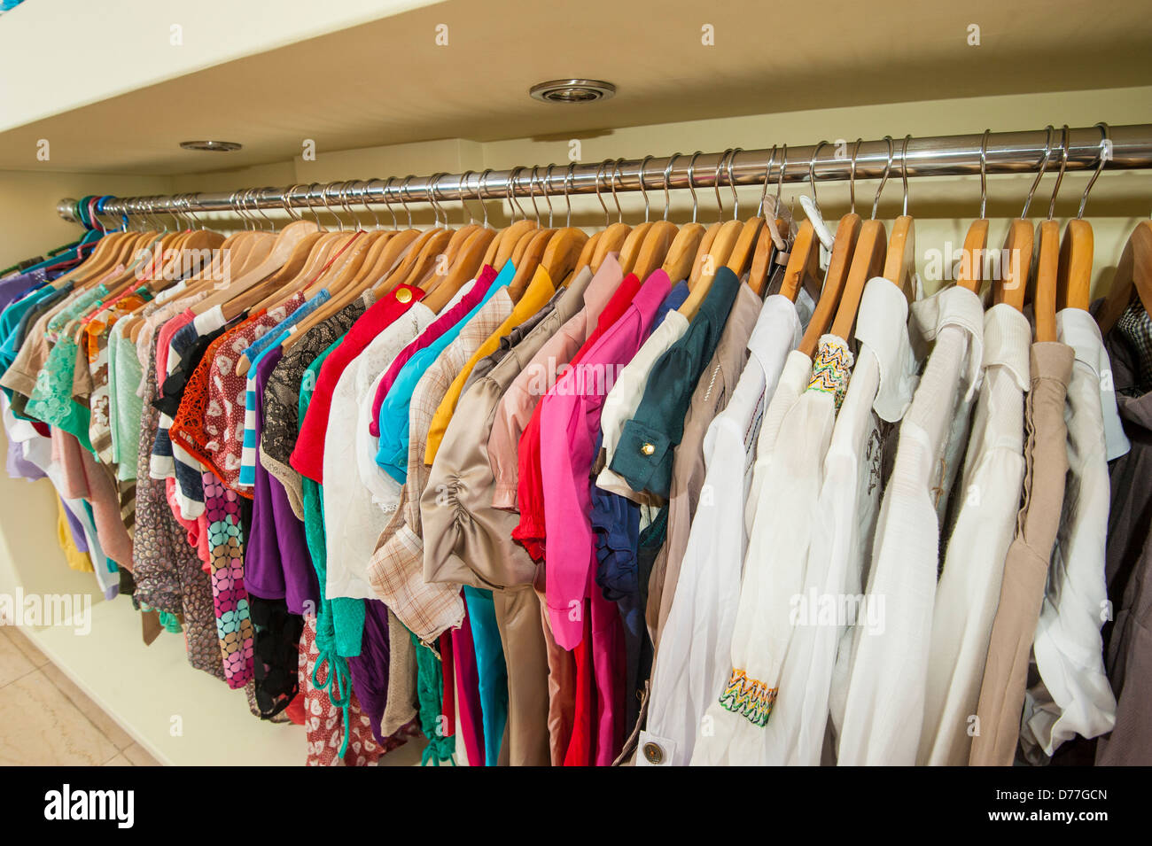 Various multicolored items of clothing hanging on hangers and rail in a shop Stock Photo Alamy