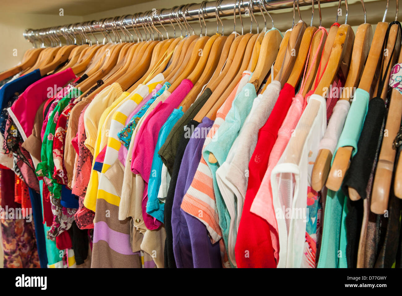 Various multi-colored items of clothing hanging on hangers and rail in ...