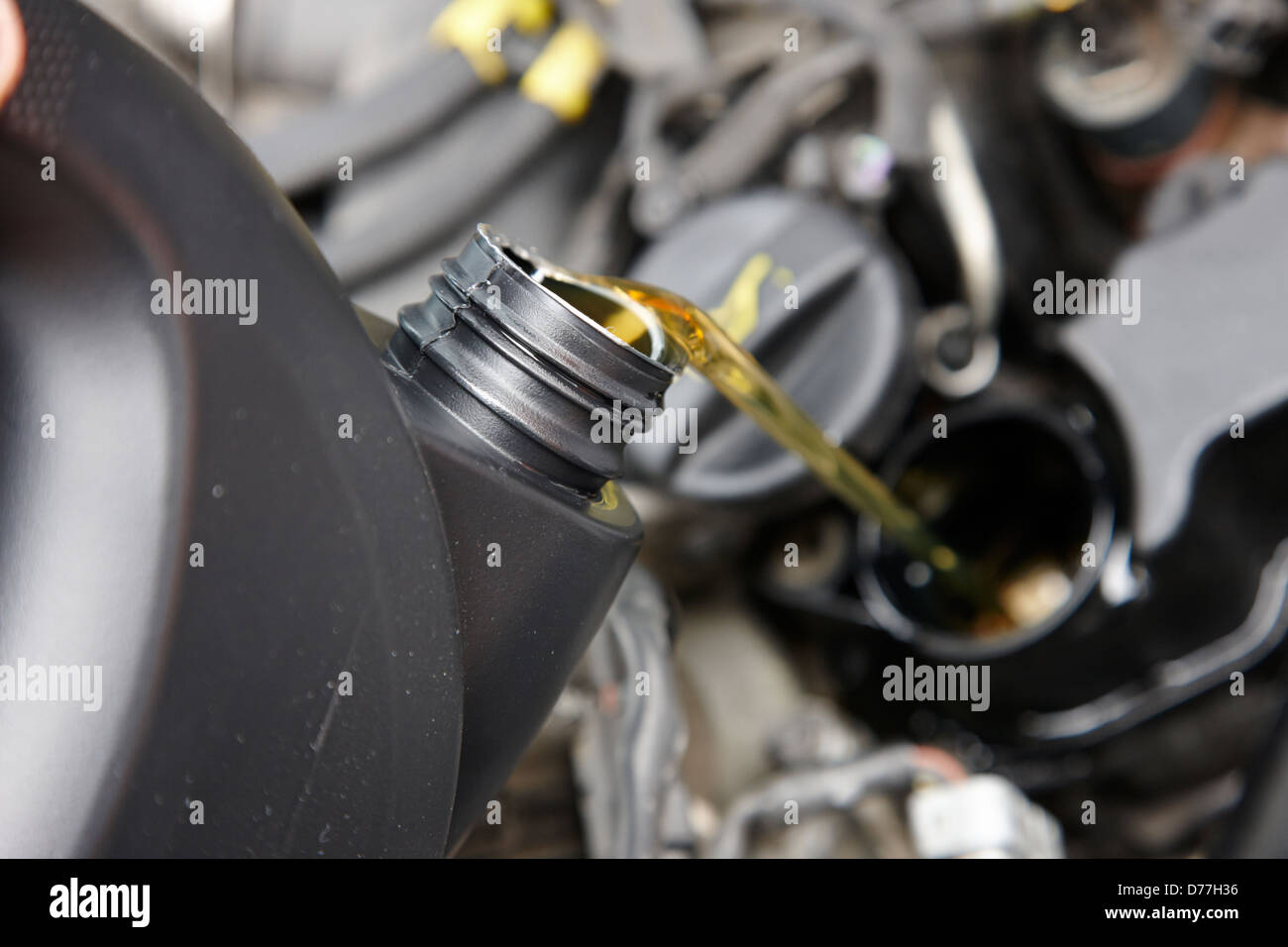 pouring fresh new oil into engine filler in a car engine compartment Stock Photo