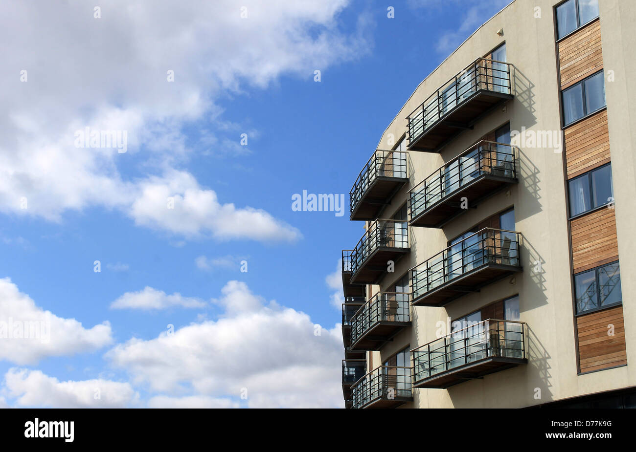 Exterior of curving modern apartment building with blue sky and cloudscape background. Stock Photo