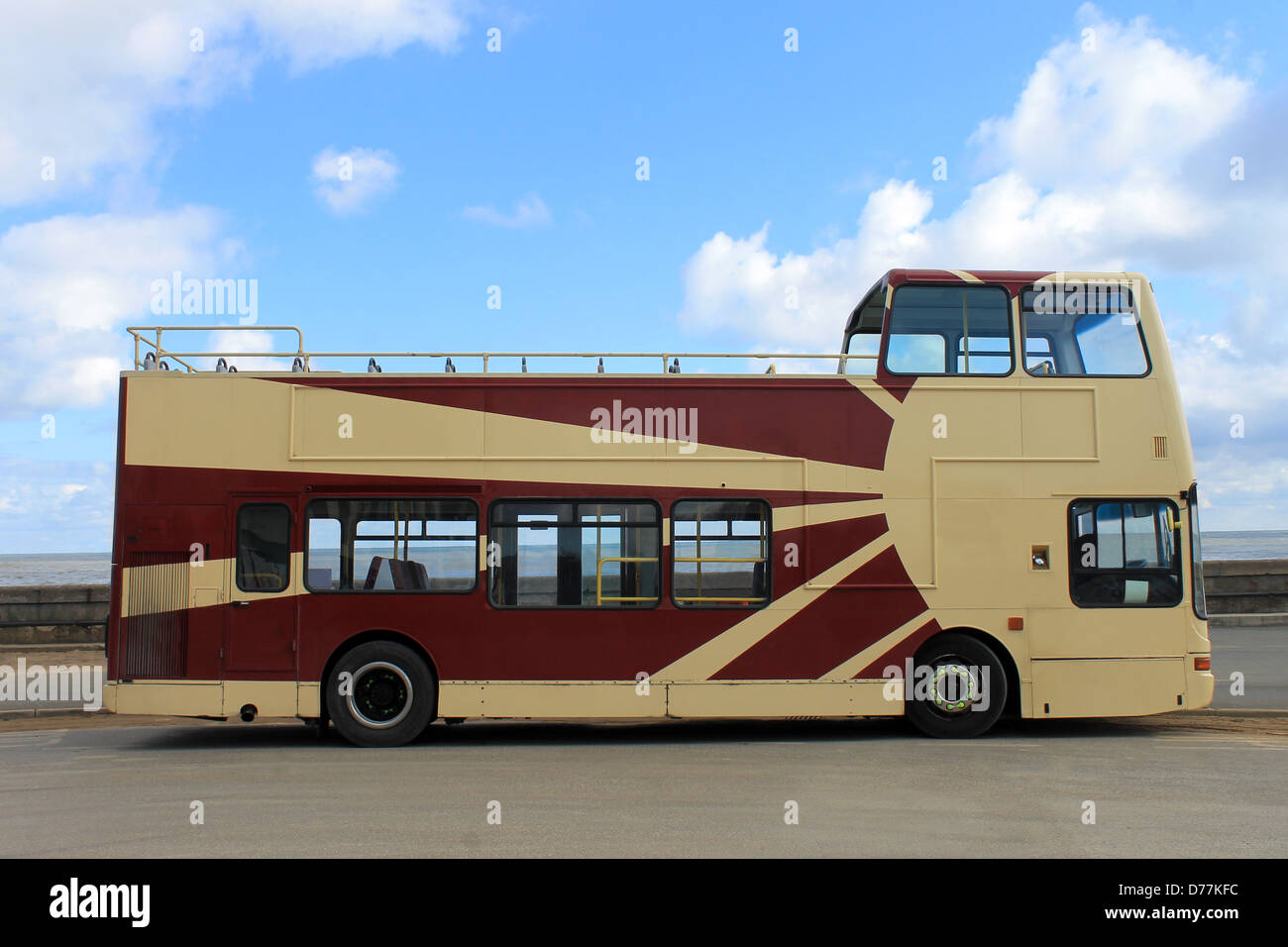 Open top tour bus parked with sea and cloudscape background. Stock Photo
