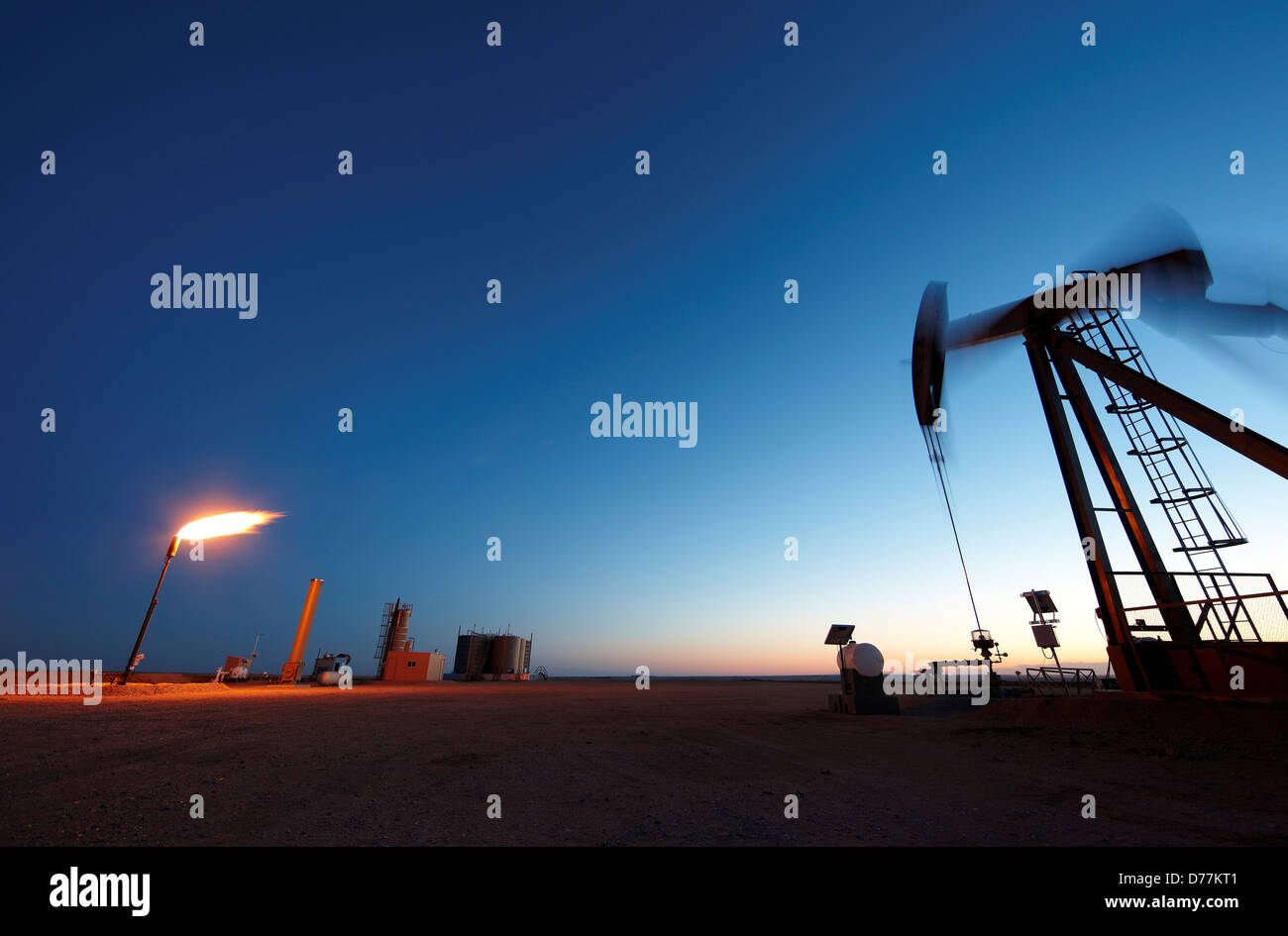 Oil well pumpjack pump jack gas flare flare stack eastern plains Colorado dusk view Oil well developed hydraulic fracturing Stock Photo