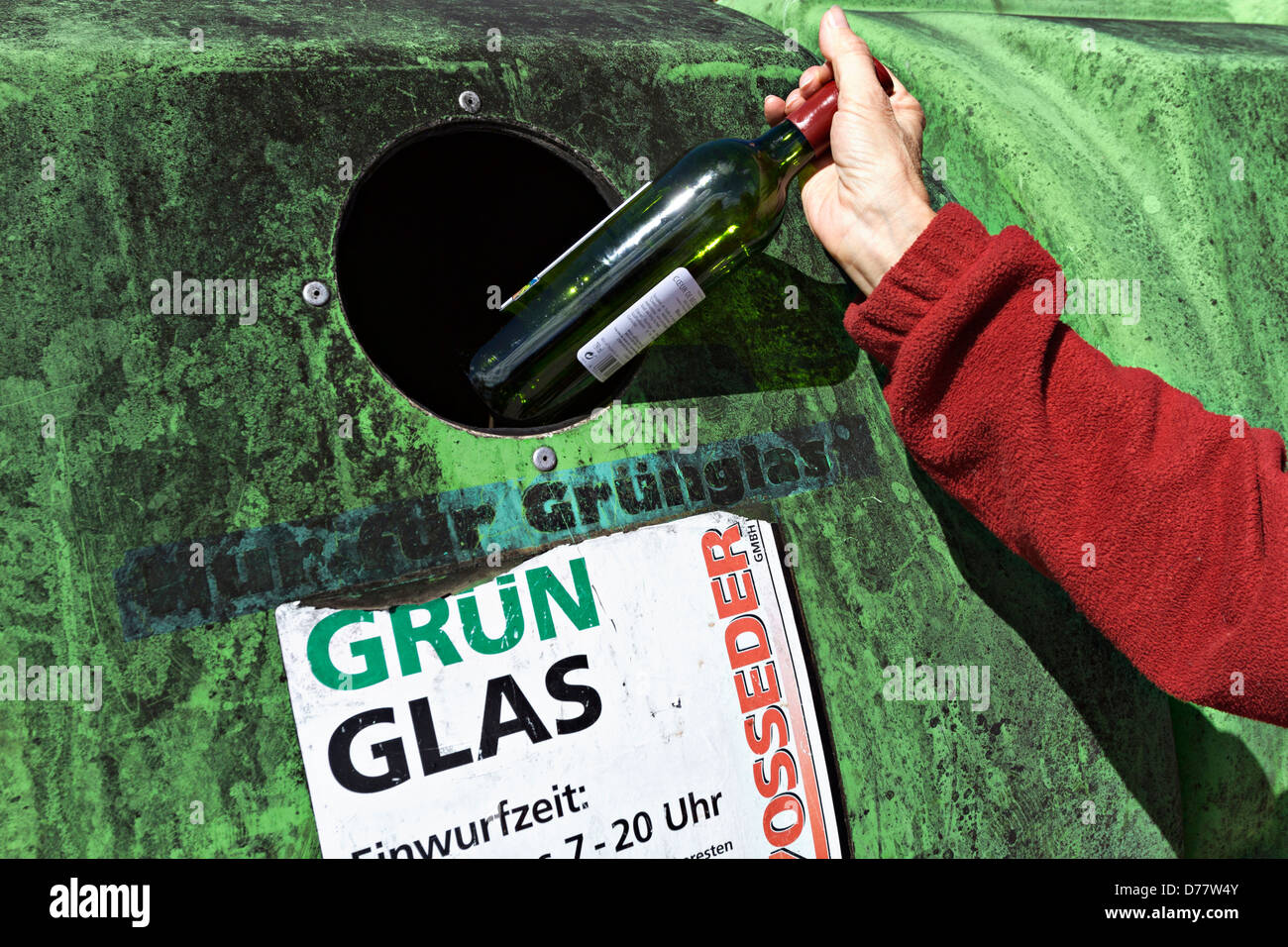 Woman placing bottle into a green glass recycling container, Prien Upper Bavaria Germany Stock Photo