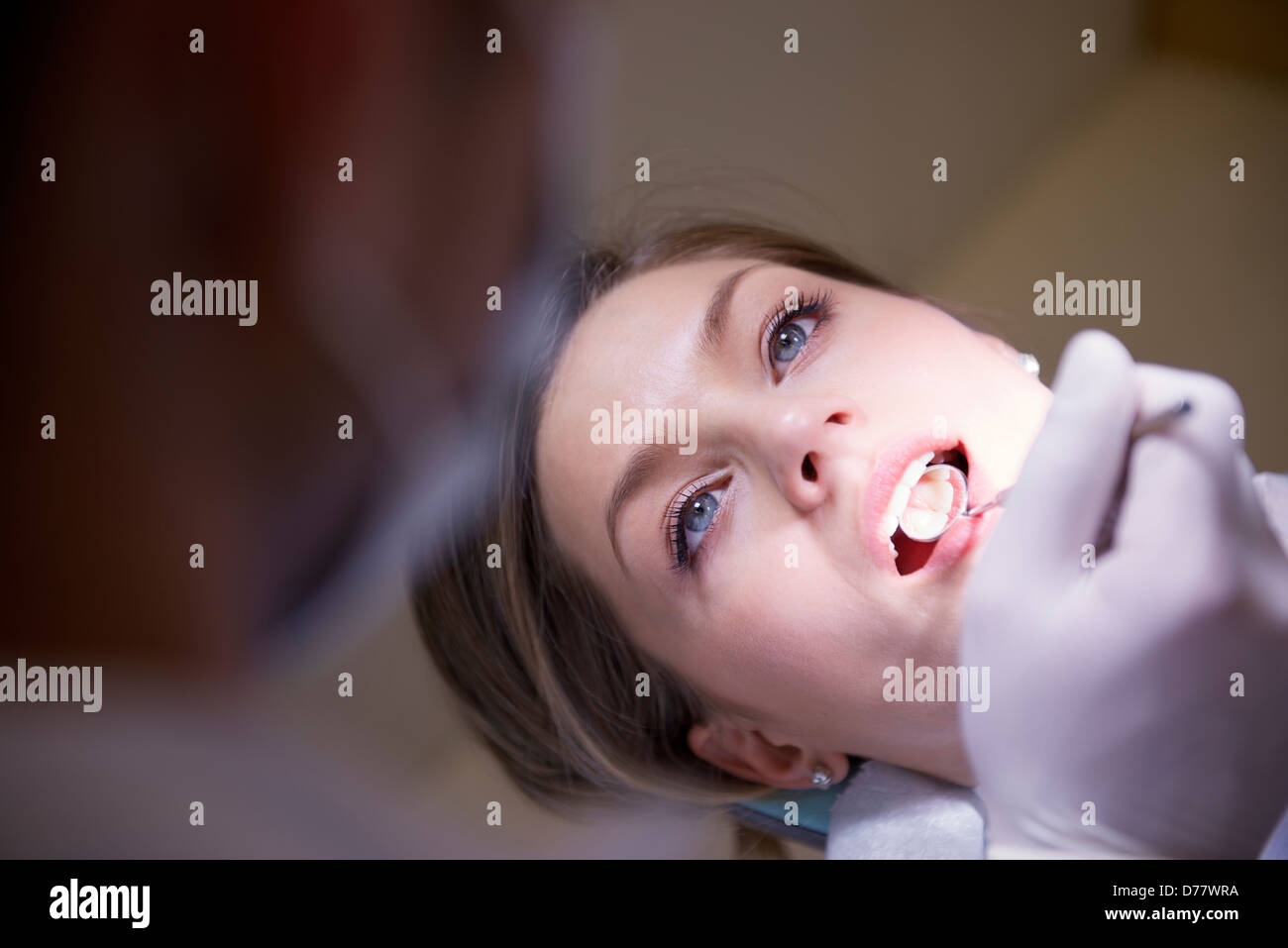 dentist checking oral hygiene of female patient lying on couch in