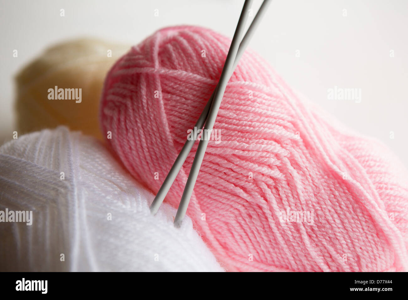 Three balls of wool with a set of knitting needles placed in one ball Stock Photo