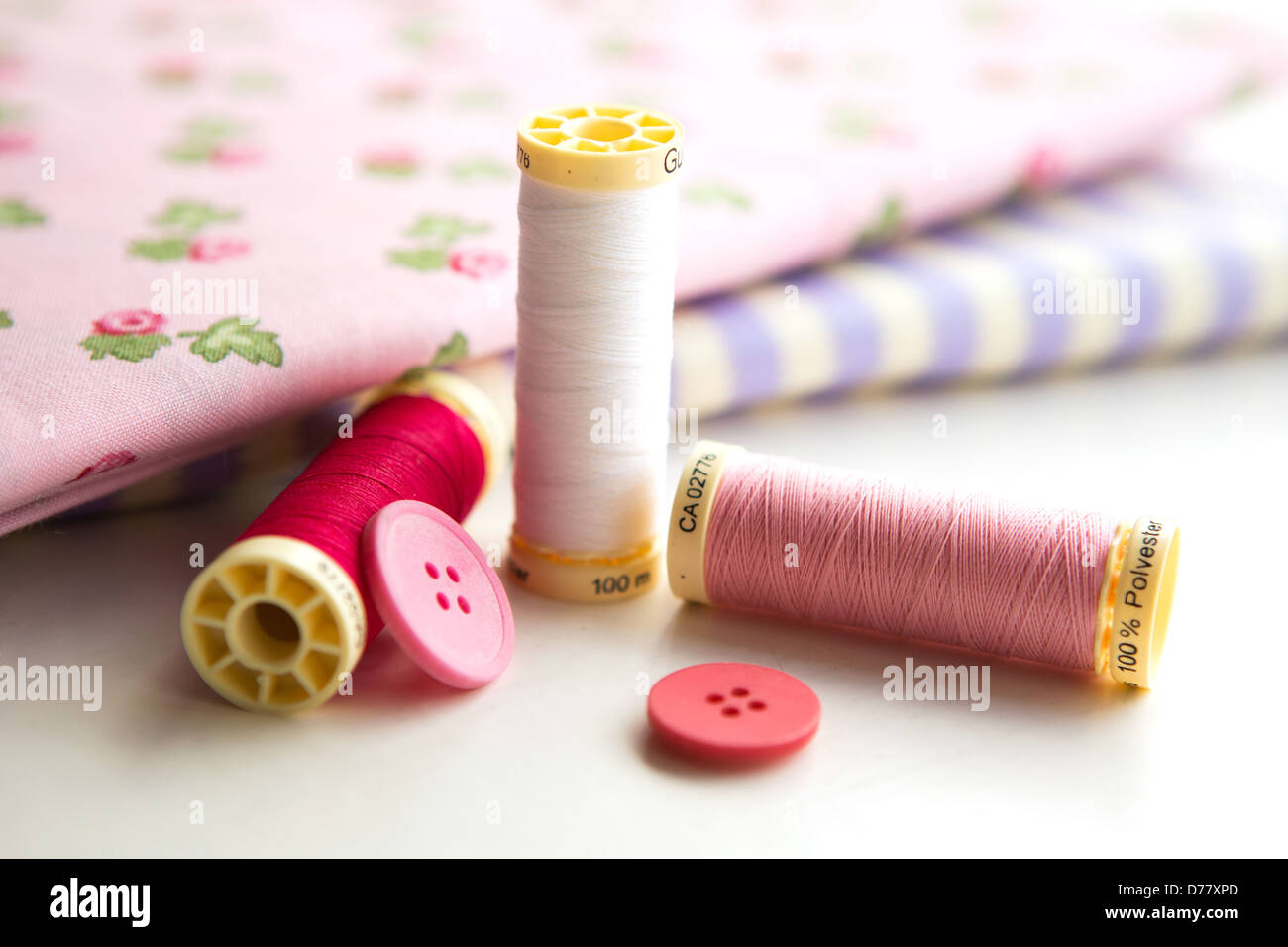 Sewing accessories - thread, fabric and buttons placed on a light grey background Stock Photo