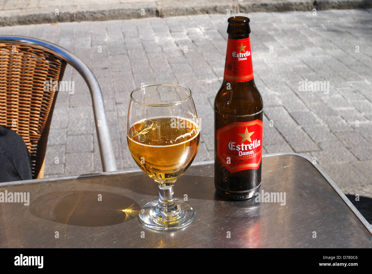Estrella Beer bottle and glass on table at a pavement cafe in Stock