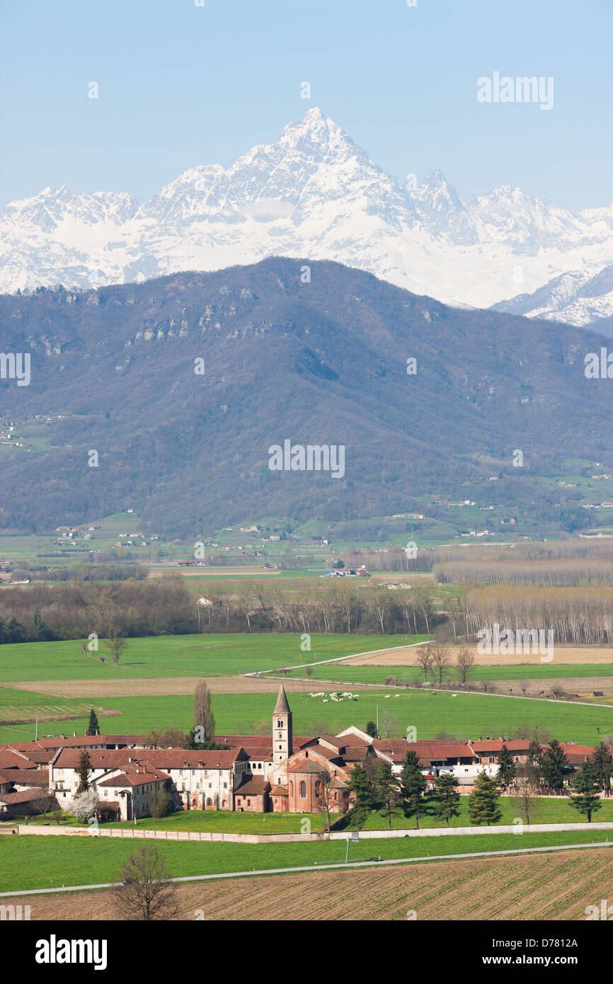 AERIAL VIEW. Staffarda Abbey in the Po Plain with Monte Viso in the distance. Near the town of Saluzzo, Province of Cuneo, Piedmont, Italy. Stock Photo