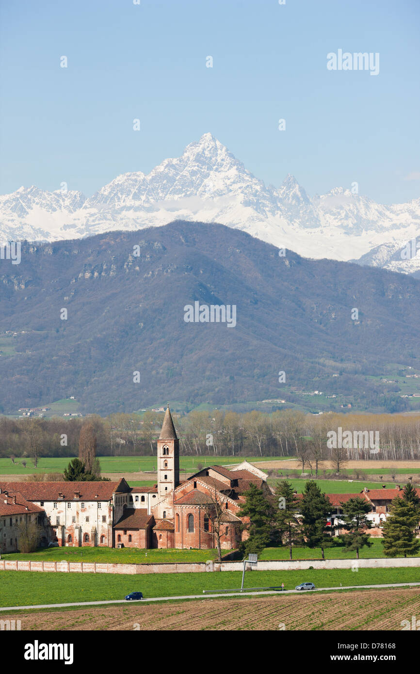 AERIAL VIEW. Staffarda Abbey in the Po Plain with Monte Viso in the distance. Near the town of Saluzzo, Province of Cuneo, Piedmont, Italy. Stock Photo