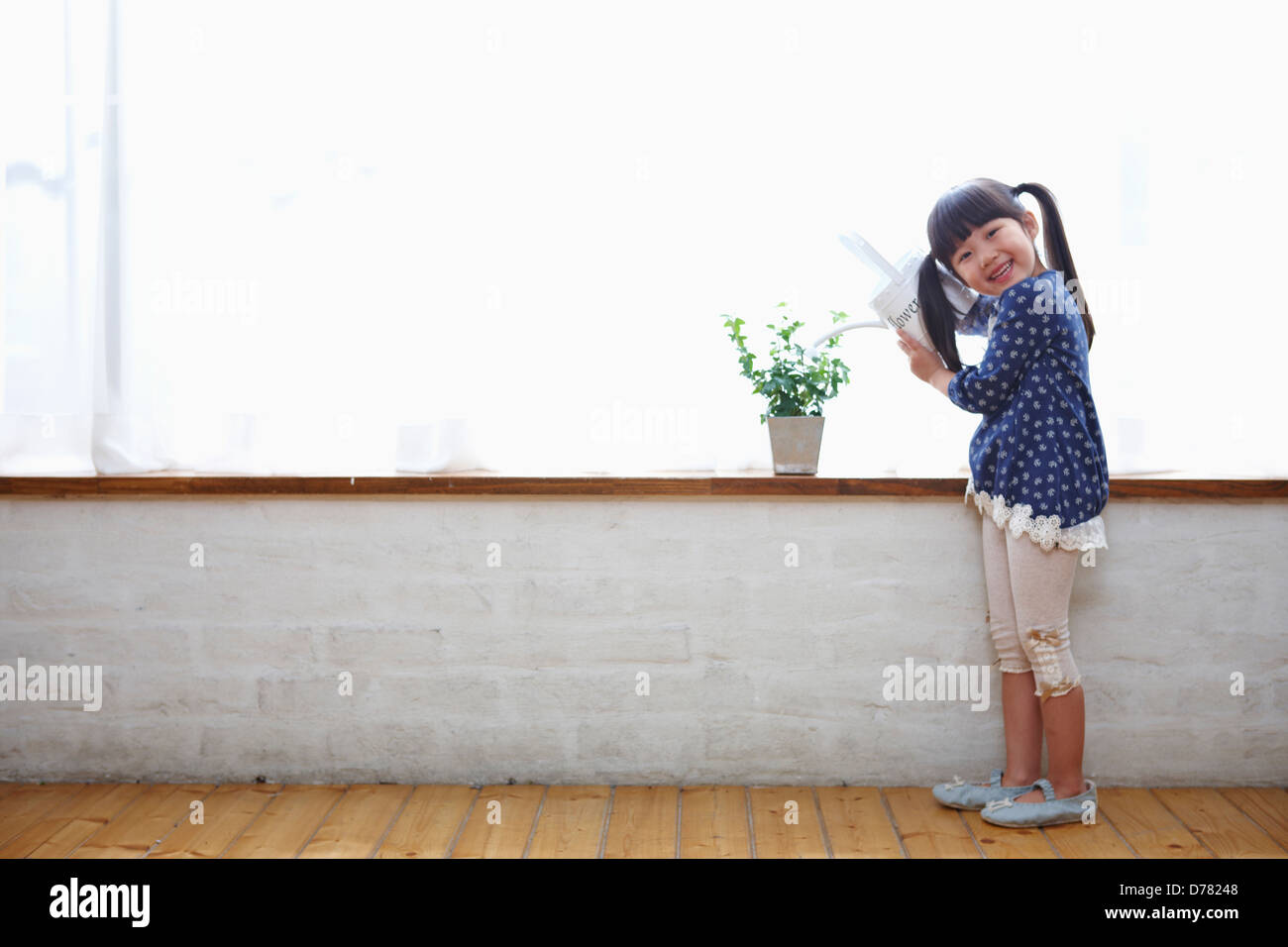 a girl watering a plant in a vase Stock Photo